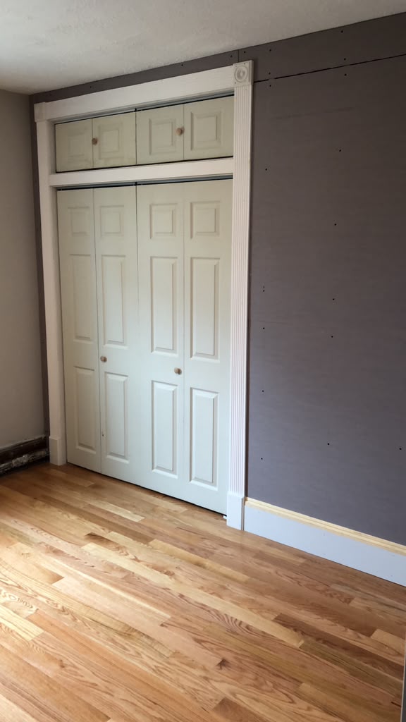 Newly installed white closet doors with custom casing and baseboard trim