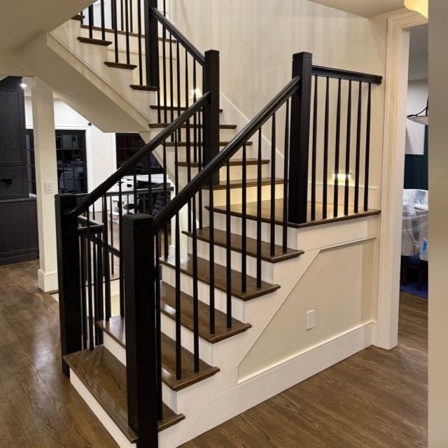 Remodeled staircase with stained hardwood treads and black metal balusters