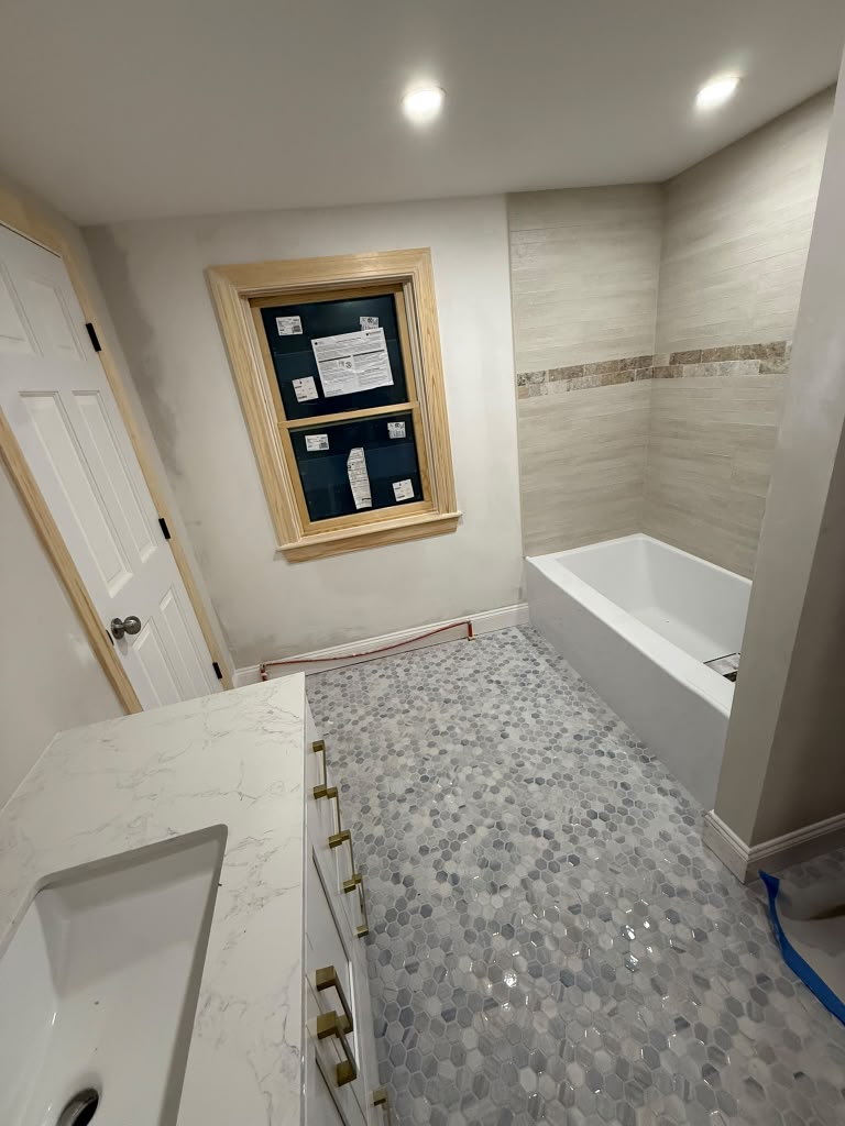 Bathroom remodel with quartz vanity, hex tile floor and tiled tub surround