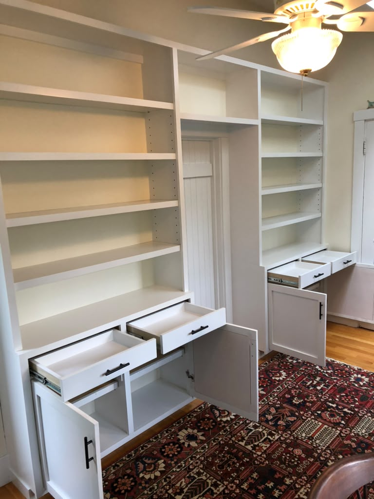 Custom white built-in bookshelves and desk unit with drawers